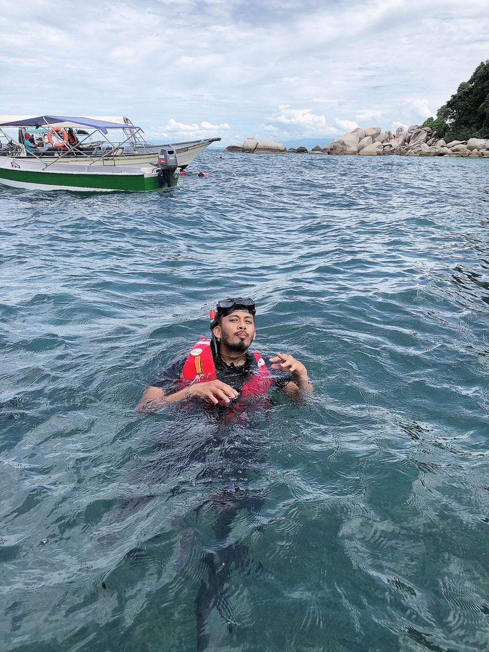 Snorkeler floating in the clear water beside the boat